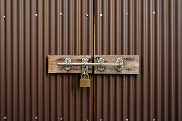 Padlock on a latch securing a brown metal gate.