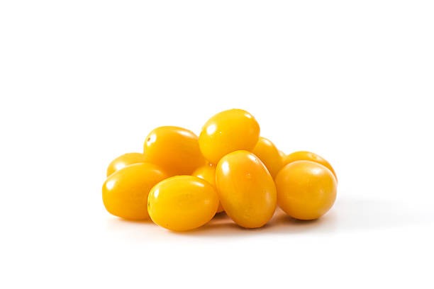 A close-up of fresh yellow cherry tomatoes piled together on a clean white background, showcasing their smooth skin, vibrant color, and freshness.