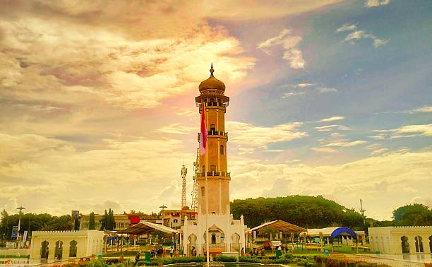 Majestic view of Baiturrahman Grand Mosque tower in Banda Aceh, Indonesia, under a golden sky. Iconic Islamic architecture and cultural landmark in Southeast Asia.