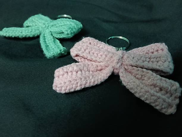 istock Handmade Crochet Keychains with Bow Designs on Dark Fabric Background 2217583005
