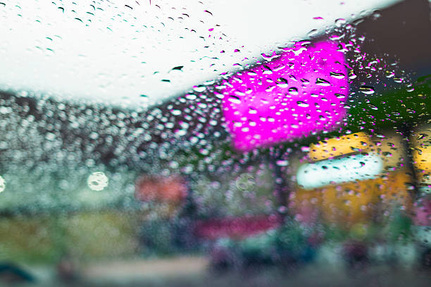 Image of car windshield with water drops stuck due to rain with blurred image of convenience store in the background concept of changing seasons lonely mood in rainy season
