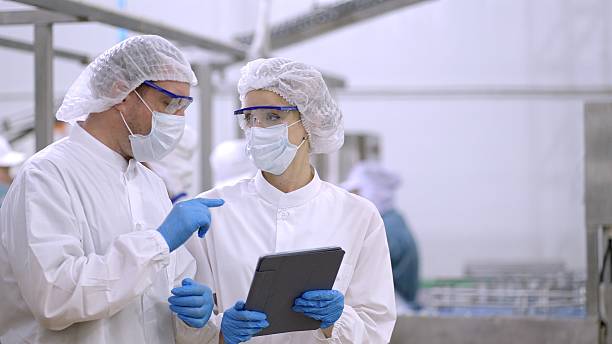 istock Product researcher or quality control engineer or production line worker in white sterile uniforms prevent contamination of food and drink product industry or cosmetic manufacturing plants or processed food or canned food, discuss about product at factory 2217587867