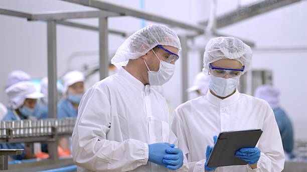 istock Engineers control quanlity and process of production by application on tablet, discussing project work about production plan at manufacturing storage. production line worker in white sterile uniforms working together in manufacturing plants. Teamwork. 2217587868
