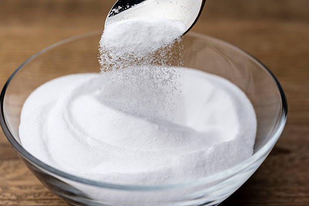 istock Scooping Baking Soda Powder from Glass Bowl on Wooden Table 2217593736