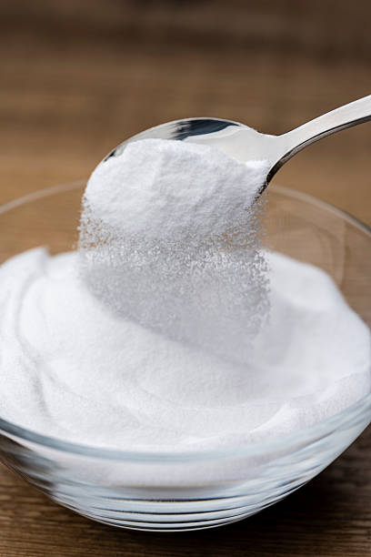istock Scooping Baking Soda Powder from Glass Bowl on Wooden Table 2217593742