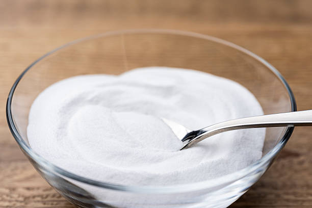 istock Scooping Baking Soda Powder from Glass Bowl on Wooden Table 2217593749