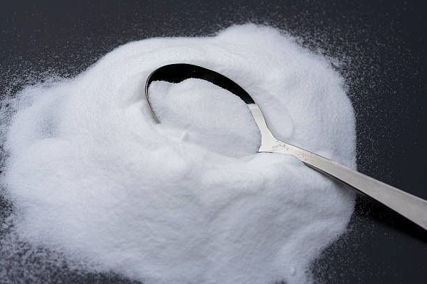 istock Silver Spoon with Baking Soda Powder on Black Background 2217593794