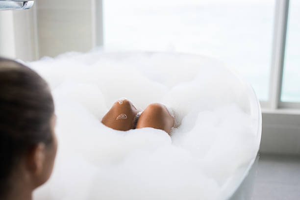 Close up of unrecognizable woman's legs relaxing on a bathtub during bubble bath.