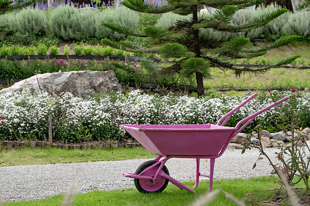 A pink cart for carrying soil is parked in the garden.