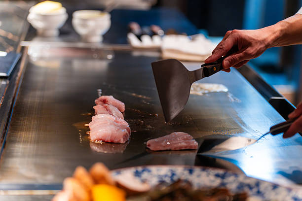 istock Chef using spatulas on Teppanyaki with Fish fillets  on Steel Hot Plate 2217597078