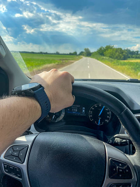 istock A man drives a car down an open rural road under a partly cloudy sky. 2217599900