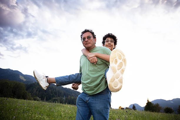Father and son joyful piggyback ride in scenic mountain field, lifestyle