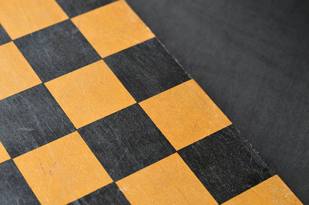 Horizontal high angle view click of blank empty textured wooden tiled chess board with old scratched scuffed weathered run down surface over black background with copy space