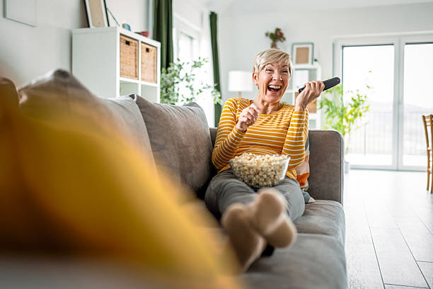 istock Senior Lady Smiling While Watching TV with a Snack 2217603936