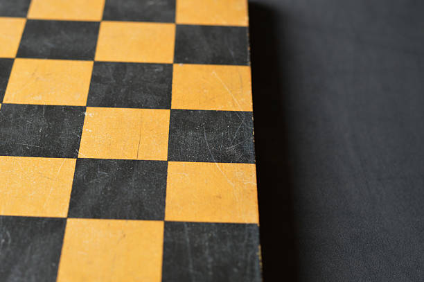 istock Horizontal table top view click of blank empty textured wooden tiled chess board with old scratched scuffed weathered run down surface over black background with copy space 2217604026