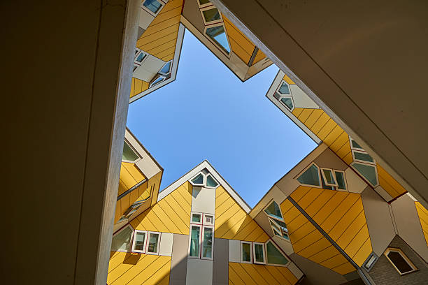 istock A unique architectural design featuring multiple yellow buildings with geometric windows forming a star-shaped opening against a clear blue sky. The perspective creates an interesting visual effect. 2217605780