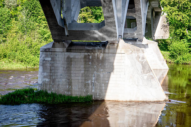 istock Concrete Bridge Pillars over Flowing River with Reflections and Green Vegetation 2217606622