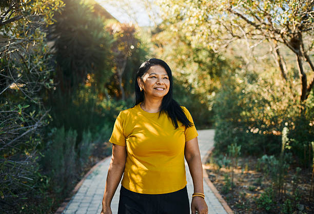 Smiling Woman Strolling Through Sunny Garden Path stock photo