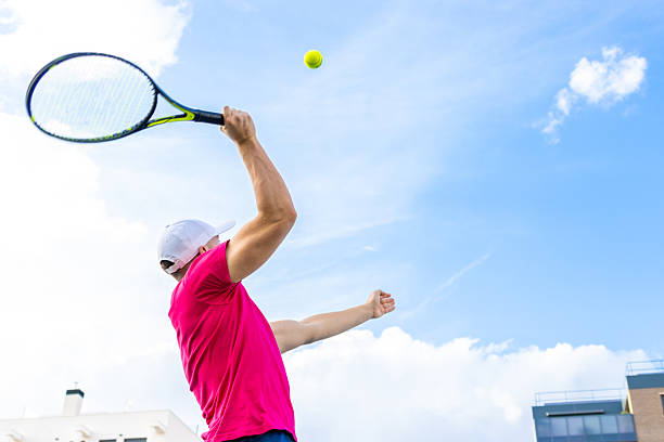 Young male tennis player serving the ball on a sunny day