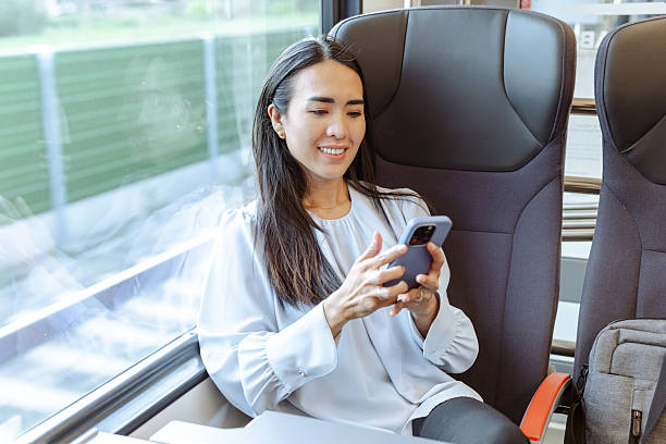 istock Smiling woman using smartphone while traveling on a train during the day 2217620791