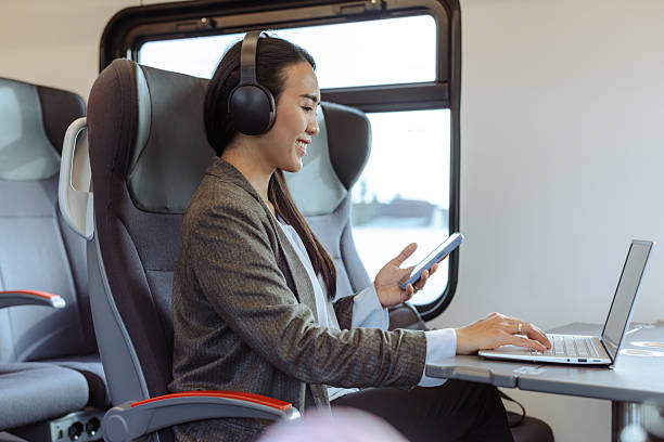 istock Woman using smartphone and laptop while traveling on modern train 2217621342