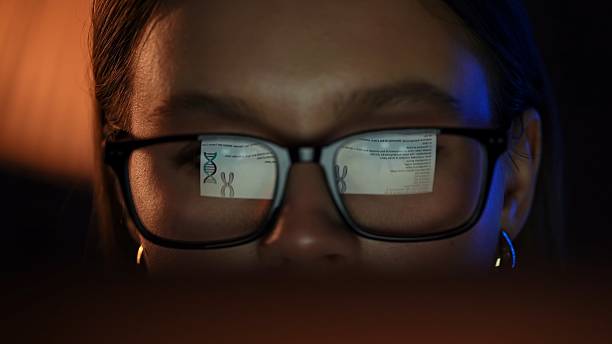 istock Focused Woman Reading Reflected DNA Document in Glasses 2217622909