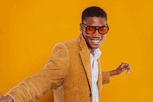 istock Stylish black man dancing and smiling on yellow background 2217624483