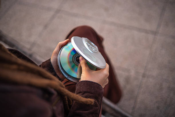 A woman with dreadlocks places a CD into her old CD player to see if it still plays - vintage tech