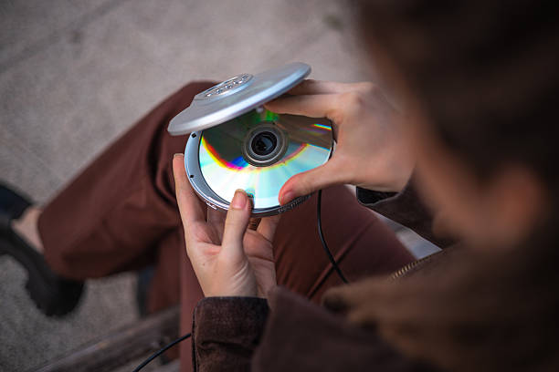 Woman carefully loads a CD into her classic player, hoping to revive the sounds of the past