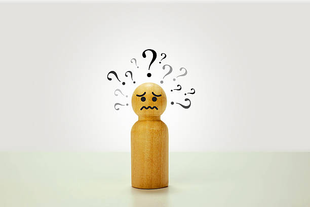 istock Sad wooden puppet with a question mark above its head, isolated on a white background. Concept of confusion, emotional struggle, and identity crisis in a symbolic and minimal design. 2217632329