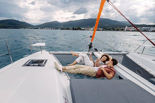 istock Young couple bonding while enjoying catamaran sailing trip together, laying on a net 2217633701