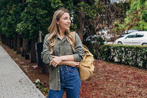 istock Young woman enjoying a leisurely stroll outdoors while carrying a backpack and embracing a casual yet stylish look in a vibrant environment 2217634828