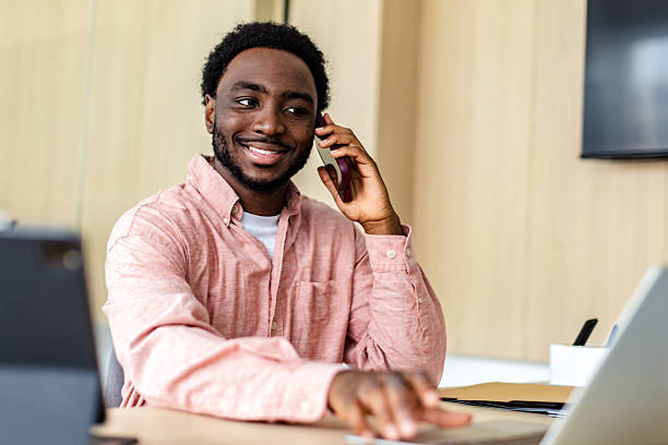 istock Young businessman confidently discussing projects on a smartphone in a modern office setting during daytime hours 2217635292