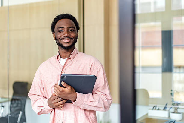 istock Young businessman showcasing confidence while holding a tablet in a modern office environment 2217636098