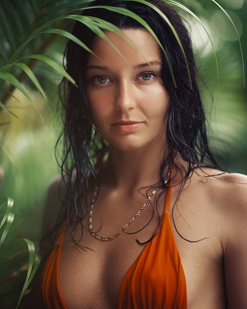 istock Exotic Woman in Orange Bikini Posing Amid Tropical Greenery 2217640939