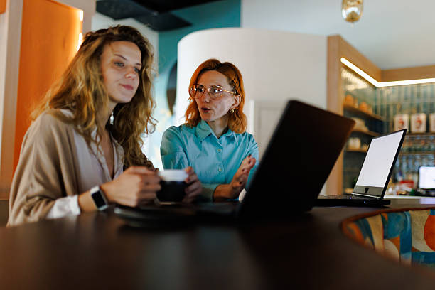 istock Businesswoman collaborating with colleague in modern workspace while discussing project details over coffee 2217643926