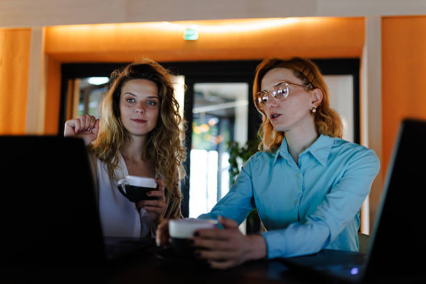 istock Businesswomen collaborating over laptops while enjoying coffee in a modern office setting during the afternoon 2217643933