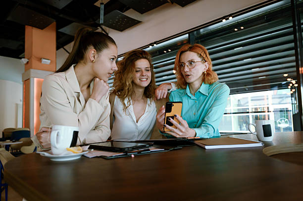 istock Three businesswomen collaborate in a modern cafe while discussing ideas and reviewing information on a smartphone during a sunny afternoon 2217643998