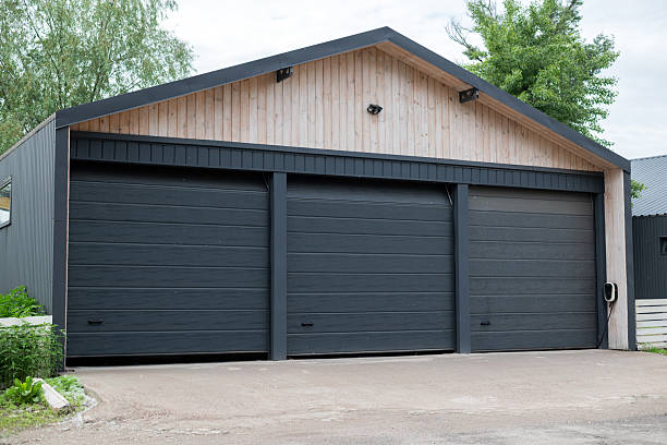 istock Modern three-door garage building with black automatic gates and light wood facade, located on a clean concrete driveway. 2217647849
