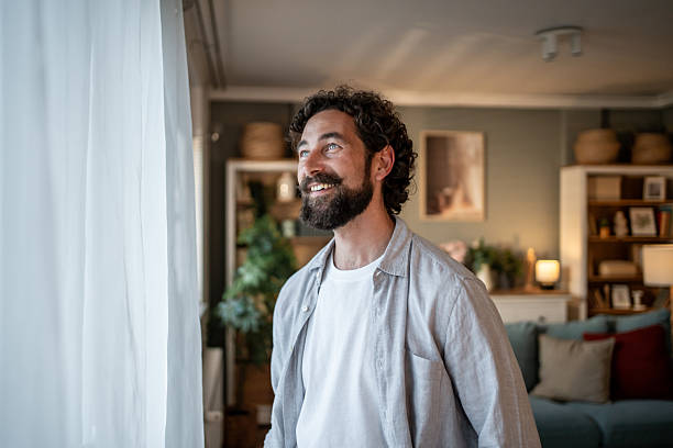 istock Smiling bearded man looking out the window at home 2217650212