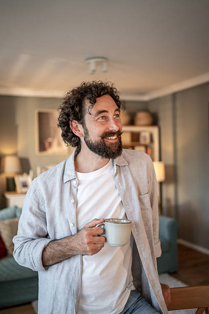 istock Smiling bearded man enjoying a cup of coffee at home 2217650331