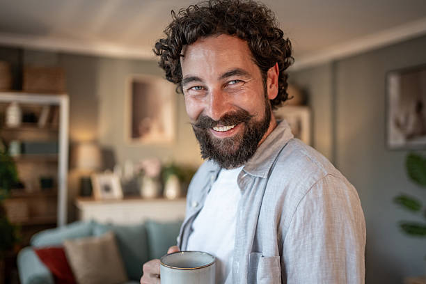 istock Smiling bearded man drinking coffee at home 2217650393