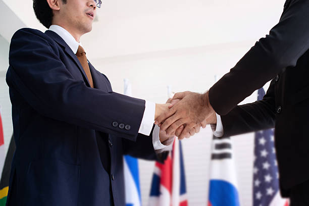 istock Business people shaking hands with international flags on blurred background 2217651699