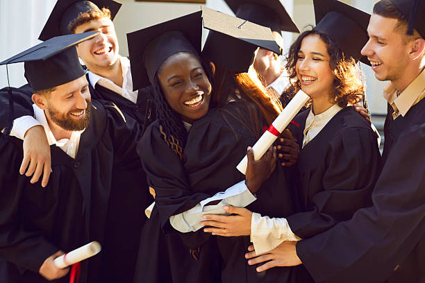 istock Smiling diverse graduates hugging each other holding diplomas and celebrating graduation. 2217656522