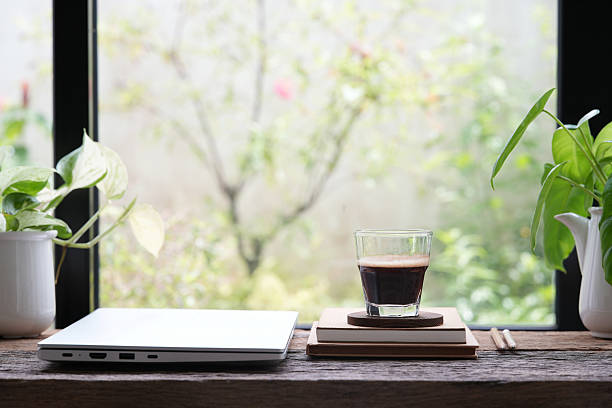 istock Folded laptop with coffee drink and plants by the window 2217658566