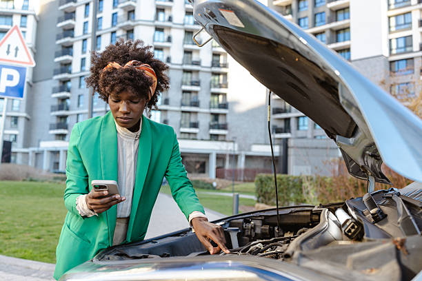 istock Woman examining car engine while holding smartphone in the city 2217665052