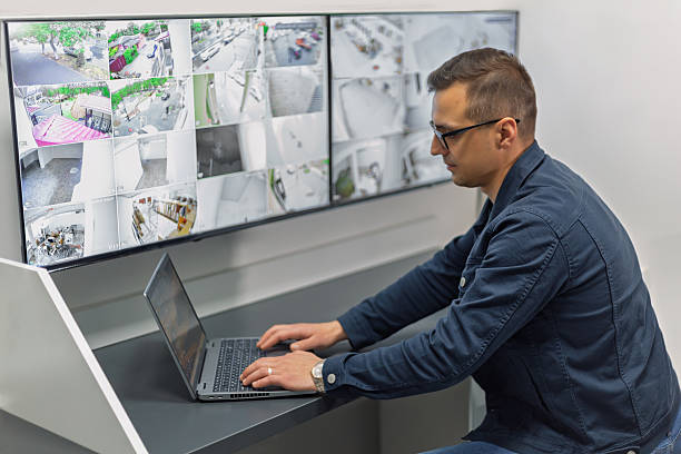 istock Security guard monitoring cctv cameras on multiple screens and using laptop 2217666066