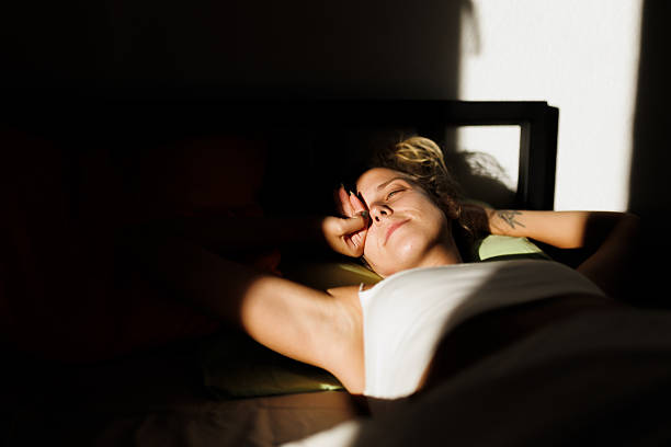 istock Relaxing woman rests peacefully in sunlight while lying on bed with serene expression in cozy room setting 2217667074