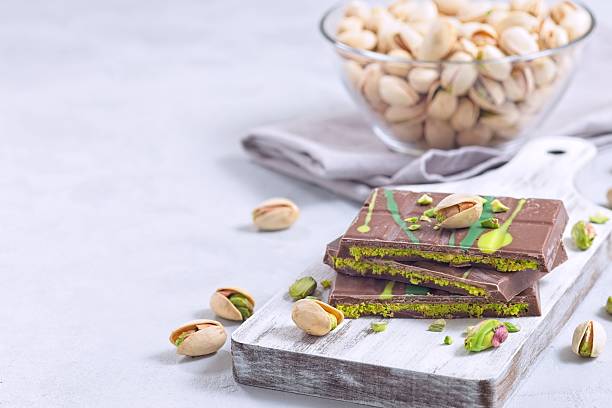 istock Milk chocolate bar with pistachio and kadaifi filing, lying on cutting board, horizontal copy space 2217670664