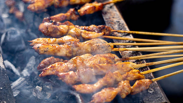 istock Chef roaested sate ayam (chicken skewer) with charcoal. Sate ayam served with peanut sauce. 2217670815